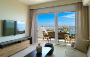 a living room with a television and a view of the ocean at Indigo Luxury apartment in Agios Nikolaos
