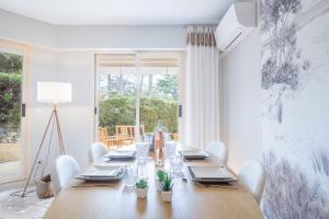 una sala da pranzo con un lungo tavolo in legno e sedie bianche di SERRENDY Garden level with swimming pool a Cannes