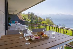 - une table en bois avec des verres à vin et du fromage sur un balcon dans l'établissement Les Terrasses de Lavaux 1 - Appartement de luxe avec vue panoramique et piscine, à Puidoux