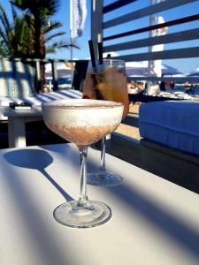 dos copas de vino sentadas en una mesa con una bebida en White Tower Mamaia Apartament 608, en Mamaia