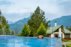 a man in a swimming pool in front of a house at Southern Panorama Campnoel Munnar in Vattavada