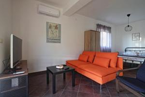 ein Wohnzimmer mit einem orangefarbenen Sofa und einem Bett in der Unterkunft Apartman Studio Pesja in Omišalj