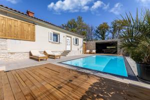 a swimming pool with a wooden deck and a house at Villa Luna in Županje