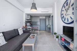 uma sala de estar com um sofá e um relógio na parede em Milva Apartments em Cidade de Kos