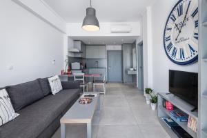 a living room with a couch and a clock on the wall at Milva Apartments in Kos