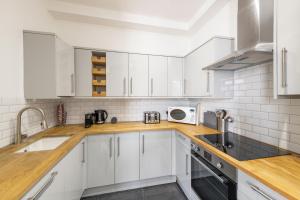 a kitchen with white cabinets and a sink and a microwave at Georgian 2 Bed Apartment with 3 Bathrooms and Parking in Bath