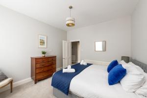 a bedroom with a bed with blue pillows and a dresser at Georgian 2 Bed Apartment with 3 Bathrooms and Parking in Bath
