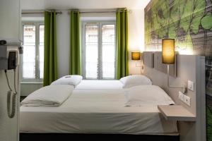 two beds in a room with green curtains at Hotel Victoria in Strasbourg