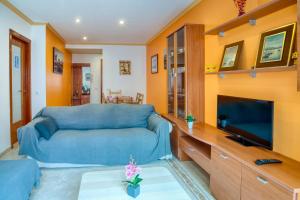 a living room with a blue couch and a tv at Apartament Yaco 2 in Lloret de Mar