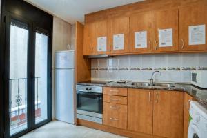 una cocina con armarios de madera y fregadero en Apartament Yaco 2 en Lloret de Mar