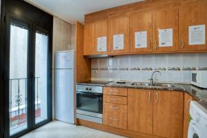 een keuken met houten kasten en een wastafel bij Apartament Yaco 2 in Lloret de Mar