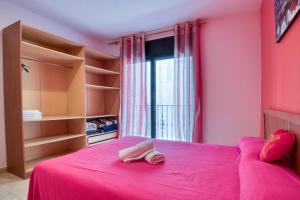 Dormitorio rosa con cama rosa y ventana en Apartament Yaco 2 en Lloret de Mar