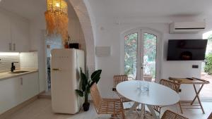 a kitchen with a white refrigerator and a table at New Boho Home with Pool, Balcony and Private Garden in Nerja