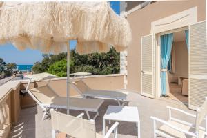 Hotel Villa Bolgheri في مارينا دي كاستانييتو كاردوتشي: فناء مع كراسي ومظلة والمحيط