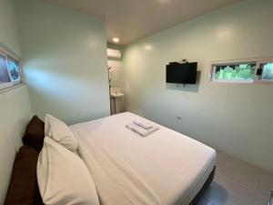 Cama blanca en habitación con TV en Makan Resort, en Kanchanaburi
