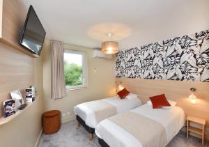 a hotel room with two beds and a tv at Contact Hôtel Astréa Nevers Nord et son restaurant la Nouvelle Table in Varennes Vauzelles