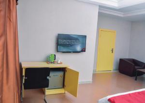 Habitación con escritorio y TV en la pared. en TRAVELLERS HOMELY, en Ado Ekiti