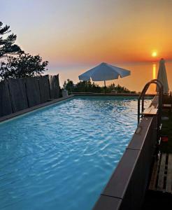 a swimming pool with an umbrella and the sunset at Vista Mare BB in Anacapri