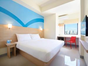 1 dormitorio con 1 cama blanca y 1 silla roja en Hop Inn Hotel Cebu City en Cebú