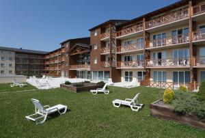 a hotel with lounge chairs on the lawn at Vacancéole - Appart'Vacances Pyrénées 2000 in Bolquere Pyrenees 2000