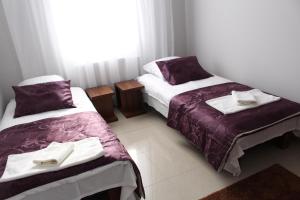ビャウィストクにあるBelwederの紫と白のシーツが備わる客室のベッド2台