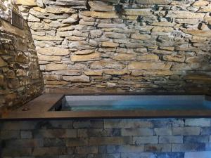 Albergo Diffuso Ca' Spiga في لاليو: جدار حجري مع حوض استحمام ساخن في الغرفة