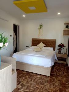 ein Schlafzimmer mit einem großen weißen Bett und einer gelben Decke in der Unterkunft HILLINGTON COTTAGE in Kodaikanal