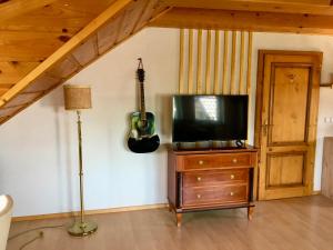 a living room with a television and a guitar on the wall at Stay Apartments Bled in Bled
