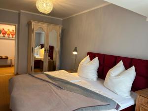 a bedroom with a bed with a red headboard and white pillows at Gästezimmer in herrschaftlicher Villa in Krakow am See