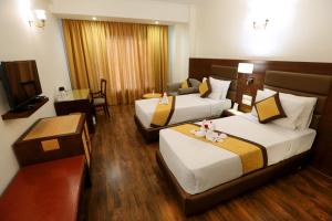 a hotel room with two beds and a table at Hotel Meraden Grand in Varanasi