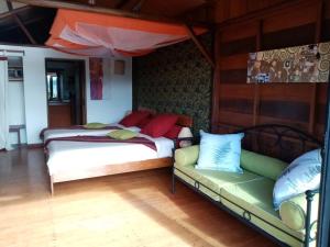 two beds and a couch in a room at Nature Lodge in Diego Suarez