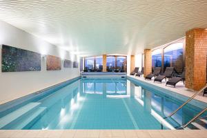 a large swimming pool with chairs in a building at Mittelburg Wellnesshotel in Oy-Mittelberg