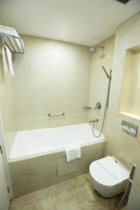 a bathroom with a bath tub and a toilet at Hotel Meraden Grand in Varanasi