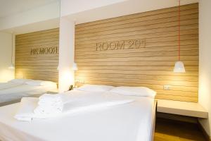 two beds in a room with a wooden wall at B612 in Levico Terme