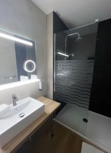 シャトライヨン・プラージュにあるLOGIS Hotel Majestic Chatelaillon Plage - La Rochelleのバスルーム(洗面台、ガラス張りのシャワー付)
