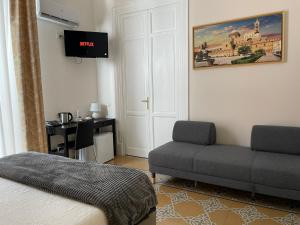 a hotel room with a bed, couch and television at Liberty Palace in Palermo