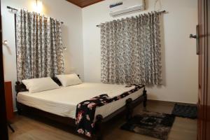 a bedroom with a bed with a window with curtains at Marari Casa Almare in Mararikulam