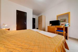 a bedroom with a bed and a desk and a television at Garni Hotel S Coast in Budva