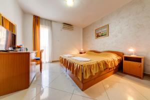 a bedroom with a bed with a yellow bedspread at Hotel Suzana Budva in Budva