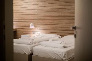 una camera con due letti con lenzuola bianche e una luce sospesa di B612 a Levico Terme