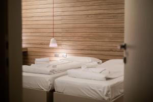 ein Zimmer mit zwei Betten mit weißen Laken und einer Hängelampe in der Unterkunft B612 in Levico Terme