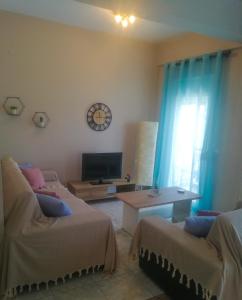 a living room with two beds and a tv at Iliada's apartment in Polychrono