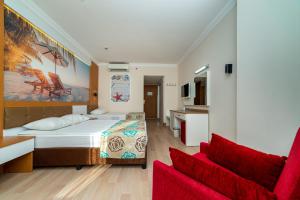 a bedroom with a bed and two red chairs at Primasol Hane Family Resort Hotel in Side