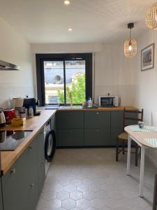 a kitchen with green cabinets and a window at Appartement d’artiste lumineux central 76m2 in Perpignan