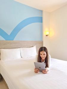 宿霧市的住宿－Hop Inn Hotel Cebu City，一位妇女躺在床上,使用笔记本电脑