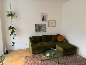 un soggiorno con divano verde e tavolo in vetro di Lovely spacious 1-bedroom flat in Tufnell Park close to Central London a Londra