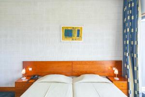 a bedroom with a bed and a lamp at Hotel Colombo in Vila do Porto