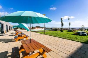 eine Gruppe von Bänken mit einem Regenschirm auf einer Terrasse in der Unterkunft Hotel Colombo in Vila do Porto