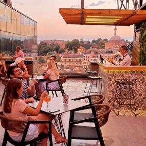 un grupo de personas sentadas en una mesa en un balcón en Hotel Arka, en Skopje
