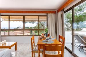 a dining room with a table and chairs and large windows at Casa Maria Elena by dracmallorca in Cala Santanyi